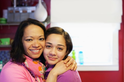 Portrait of mother hugging daughter in kitchen
