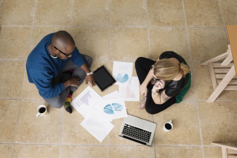 Young business partners sitting on floor in design office