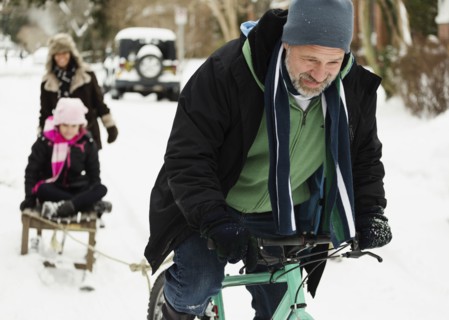 Parents and daughter playing with toboggan in snow