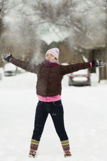 Teenage girl throwing powdered snow mid air in street