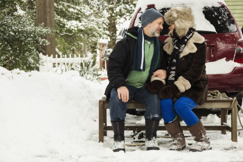 Mature couple sitting on toboggan in snow