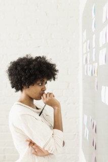Young woman reading adhesive notes on wall