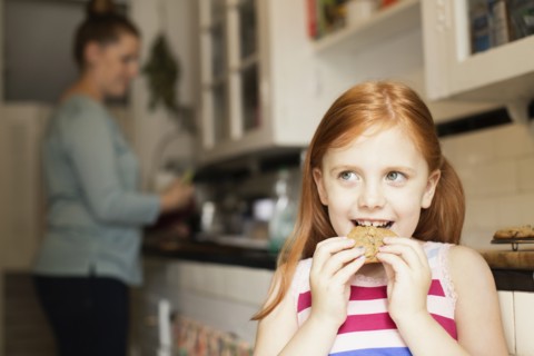 Girl eating biscuit in kitchen
