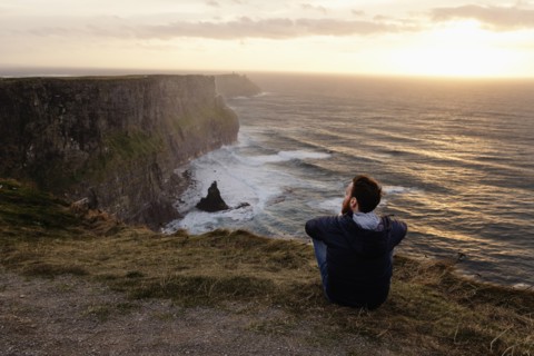 Mid adult man sitting on The Cliffs of Moher