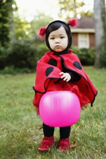 Young girl dressed up as ladybird with trick or treat bucket