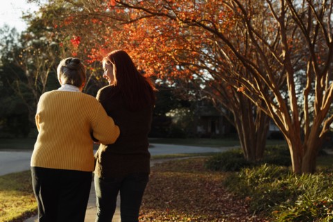 Rear view of senior woman and adult daughter strolling in suburban park