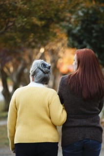 Rear view of senior woman and adult daughter strolling in autumn park