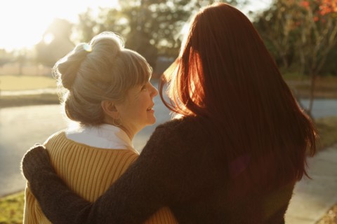 Rear view of senior woman and adult daughter strolling in park