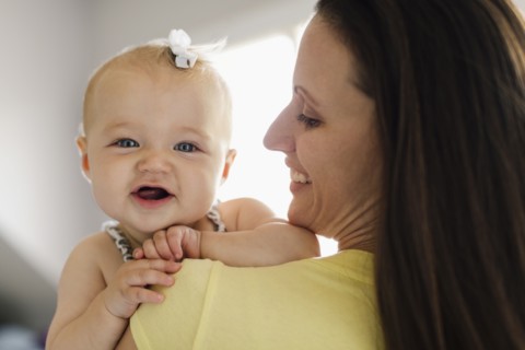 Over the shoulder portrait view of happy baby girl and mid adult mother