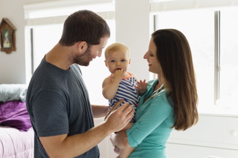 Portrait of mid adult couple with baby daughter in bedroom