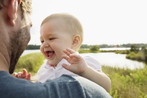 Over shoulder view of mid adult man carrying baby daughter on riverside