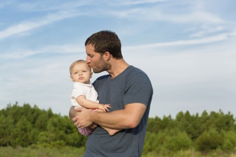 Mid adult man kissing baby daughter on cheek in rural outdoor
