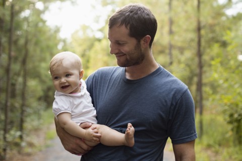 Happy mid adult man carrying baby daughter on forest track