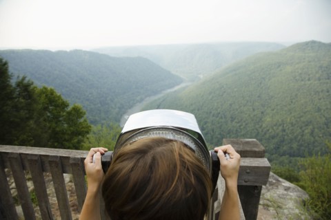 Mid adult woman looking through coin operated binoculars