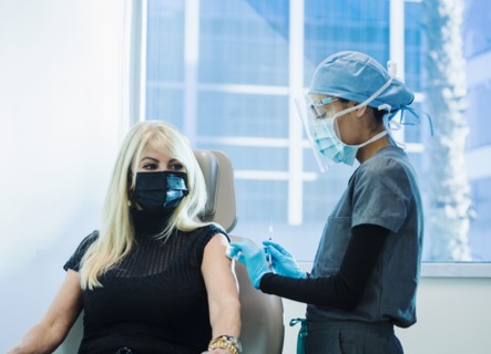 Woman in face mask receiving Covid-19 vaccination