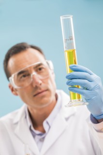 Scientist looking at yellow liquid in measuring beaker