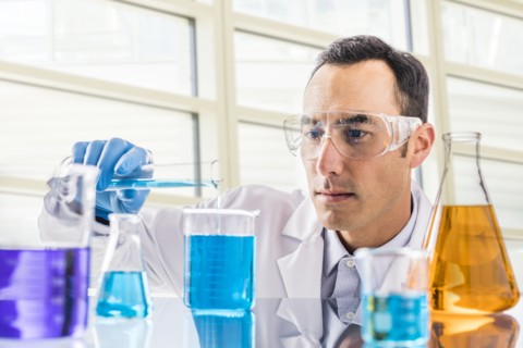 Scientist pouring blue liquid in laboratory