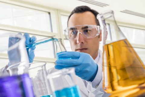 Scientist pouring blue liquid in laboratory