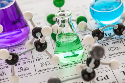 Molecular models and laboratory glassware with liquids on periodic table