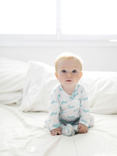 Baby boy sitting on bed