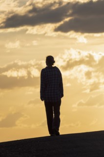 Silhouette of woman standing against sunset sky