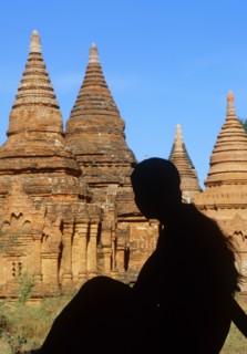 Silhouette of young woman sitting in front of Buddhist pagodas