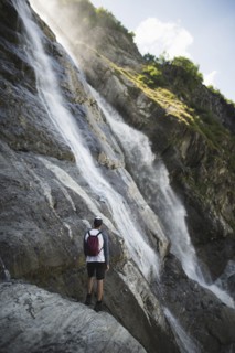 Man standing near Sofiyskiye Vodopady waterfall in Caucasus Mountains