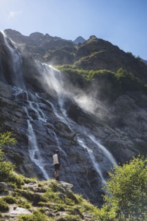 Man standing near Sofiyskiye Vodopady waterfall in Caucasus Mountains