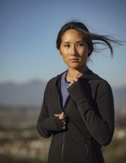 Portrait of pensive woman in sports clothing standing in landscape