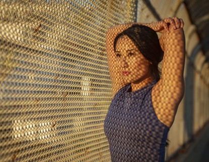 Athlete woman stretching at fence