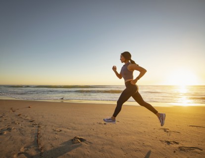 Woman jogging on beach at sunset