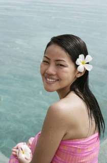 Portrait of smiling woman with frangipani flower in hair