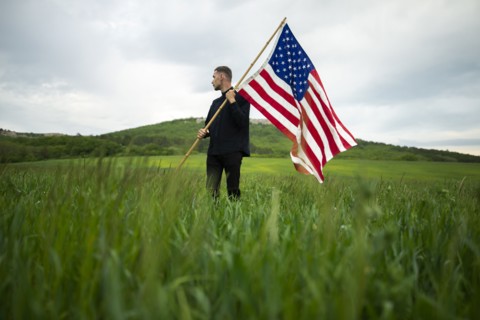 Young man with American flag in wheat field