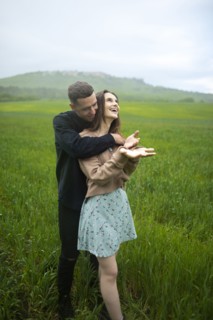 Young couple embracing in wheat field in rain