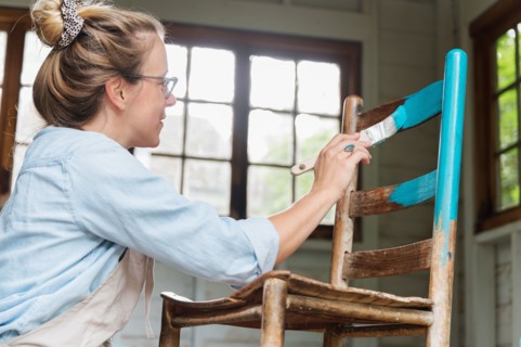 Woman painting old wooden chair