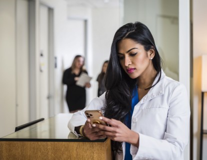 Female doctor with smart phone at reception desk