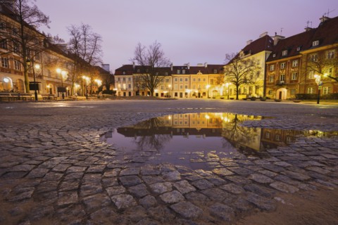 Poland, Masovia, Warsaw, Illuminated town square reflecting in puddle at night