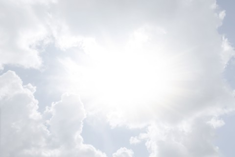 Sun shining through white clouds