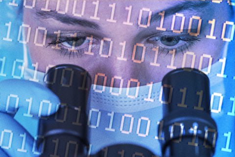 Close-up of female scientist in face mask looking int microscope