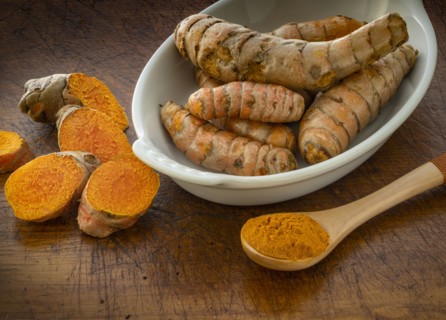 Turmeric powder and root on wooden surface