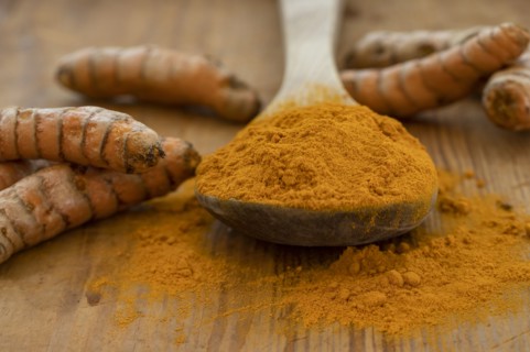 Turmeric powder and root on wooden surface