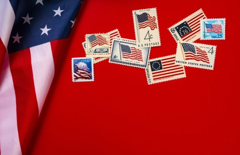 Retro postage stamps and American flag against red background