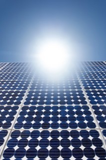 Solar panels with bright sunburst in blue sky