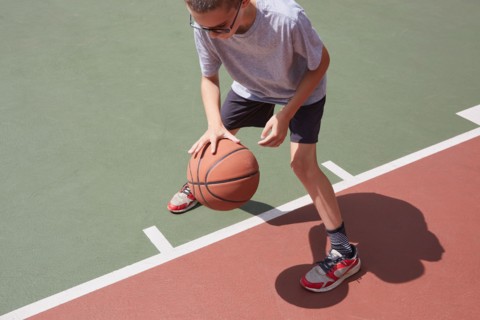 Boy dribbling basketball in park