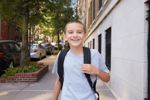 Portrait of smiling Boy wearing backpack in city