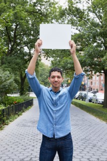 Portrait of man holding blank sign