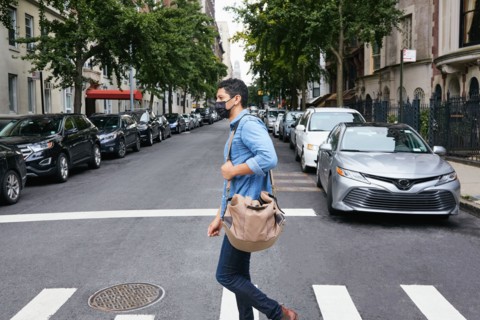 Man in face mask crossing street in city