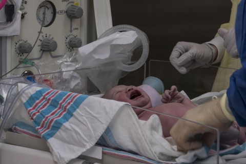 Doctors with crying newborn baby girl