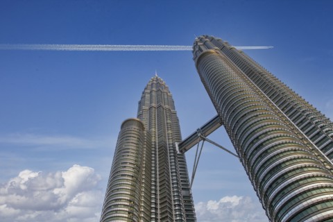 Commercial jet flying over Petronas Towers