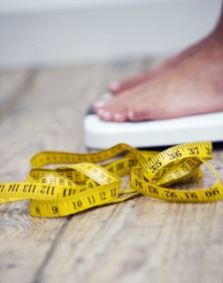 Tape measure next to woman standing on scale